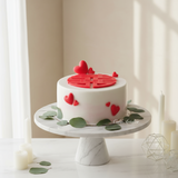 A white agar agar cake with a red 'Xi' symbol in the center, surrounded by heart-shaped decorations.